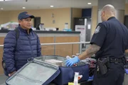 Der CBP-Aufsichtsbeamte Pacheco befragt einen Passagier, w&auml;hrend er dessen Habseligkeiten in Atlanta, Ga. durchsucht.