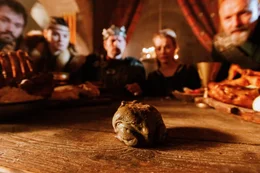 Gai hat es in seiner Froschgestalt zur gro&szlig;en &Uuml;berraschung der Feiernden bis in den Festsaal von Burg Fels geschafft. Hier wiederholt er das, was ihm Prinzessin Matilda am Brunnen versprochen hat: Er will bei ihr in ihrem Bett schlafen.