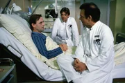Dr. Rens (Holger Petzold, l.) ist plötzlich erkrankt. Er sieht einer Operation entgegen. Auch ein Arzt kann Angst vor einer Blinddarmoperation haben. Professor Brinkmann (Klausjürgen Wussow, r.) und sein Sohn Udo (Sascha Hehn, M.) versuchen ihm gut zuzusprechen.