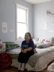 Natalia sits on her bed the morning of her adoption day.