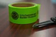 Eine Rolle aus gr&uuml;nem Klebeband mit der Aufschrift &bdquo;U.S. Customs and Border Protection&ldquo; liegt auf einem Tisch neben einem Messer im Rio Grande Valley, Texas.