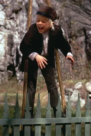 Michel (Jan Ohlsson) hat sich von einem Freund Stelzen ausgeliehen und versucht nun, damit zu laufen.