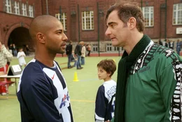 Zwischen Koofi (Tyron Ricketts, l.) und Jonas (Dario Fosca, M.) hat sich eine r&uuml;hrende Beziehung entwickelt: So begleitet Koofi Jonas zu einem Fu&szlig;ballspiel - und trifft dort ausgerechnet auf Edmund Kr&uuml;ger (Heinrich Schafmeister, r.), der ihm eine erschreckende Mitteilung macht ...