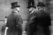 Der Finanzier John Pierpont Morgan (Mi.) diskutiert mit zwei Geschäftsleuten.