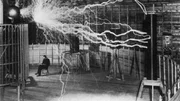 Erfinder und Wissenschaftler Nikola Tesla in seinem Labor, w&auml;hrend sein Vergr&ouml;&szlig;erungssender Hochspannungsgenerator Blitze von Elektrizit&auml;t erzeugt. Dezember 1899.