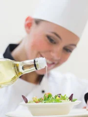 Smiling woman chef dressing a salad