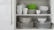 white crockery stacked in cupboard with green bowl