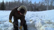 Bob Wright digs out a beaver trap.