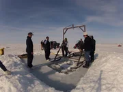 The crew of the Shamrock maneuver a gantry over their dive hole.