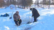 Charlie Wright (L) takes a break while his son, Bob Wright (R), chips through the ice to get a beaver trap.