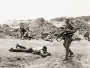 A US soldier guards bound Cuban and Grenadan prisoners at the Point Salines Airfield during the Grenada Invasion.