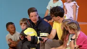 Moderator Christoph Hirschler und sein Gast, Feuerwehrfrau Katja, sitzen umgeben von neugierigen Kindern und beantworten deren Fragen rund um das Thema Feuerwehr.
