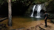Forrest Galante standing by a waterfall looking off.