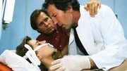 Dr. Stefan Frank (Sigmar Solbach, Mi.) und Chefarzt Dr. Ulrich Waldner (Hartmut Becker) k&uuml;mmern sich um den Notfall Vera Junghans (Karin Thaler).