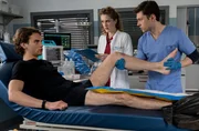 Elly Winter (Juliane Fisch, M.) und Florian Osterwald (Lion Wasczyk, r.) untersuchen das Knie von Daniel Harder (Luis Pintsch),
