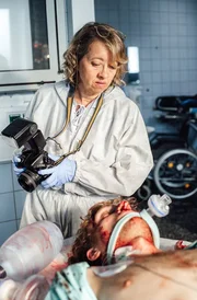 Dr. Henny Wenzel (Anna Böttcher) untersucht den Leichnam von Andreas Schneider (Nils Bannert). Dr. Henny Wenzel (Anna Böttcher) untersucht den Leichnam von Andreas Schneider (Nils Bannert).