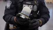 Ein CBP-Beamter hält ein Maschinenteil, das in einer Sendung gefunden wurde, und untersucht es auf versteckte Schmuggelware (National Geographic).
