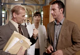 Dr. Meltzer (Karl Kranzkowski, links) erkl&auml;rt seinem Untergebenen Dr. Peter Grainernapp (Heio von Stetten, rechts) und dessen Kollegin Anja Lohse (Dana V&aacute;vrov&aacute;) ganz nebenbei, dass sie die &Auml;rmel hochkrempeln m&uuml;ssen: die feierliche Pr&auml;sentation ihres gro&szlig;en Projektes wurde um einige Wochen vorverlegt.
