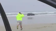 Tim Tesseneer running to a van in the ocean after hearing screams for help coming from inside