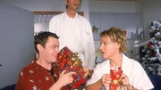 Tim (Oliver Reinhard, l.) und Nikola (Mariele Millowitsch) packen Weihnachtsgeschenke aus, was von Schmidt (Walter Sittler) neugierig be&auml;ugt wird.