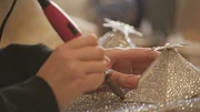 Mit ruhiger Hand werden funkelnde Kost&uuml;me Stein f&uuml;r Stein verziert.