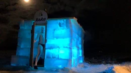 Ein Mann verl&auml;sst im Dunkeln die von innen beleuchtete Eis-Sauna in Lappland.
