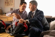 Dr. Philipp Brentano (Thomas Koch, li.) und Dr. Rolf Kaminski (Udo Schenk, re.) werden mit einem Autorenn-Simulator gegeneinander antreten. Doch bevor der Wettkampf beginnt, ringt Kaminski Philipp noch einen Deal ab.