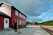 Die Nordlandsbahn in Norwegen bei L&oslash;nsdal: Der Fahrdienstleiter wechselt die Flagge, bevor der Zug kommt.