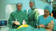 Dr. Stefan Frank (Sigmar Solbach, l.) muss die hochschwangere Marion Hansen (Susanne Bentzien, r.) operieren. Dr. Ulrich Waldner (Hartmut Becker) und Dr. Ruth Waldner (Dorothee Reize) assistieren.