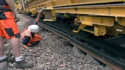 Arbeiter kontrollieren die Genauigkeit des Gleisumbauzuges