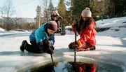 Simon (Oskar Lindquist), Lars (Bj&ouml;rnar Lysfoss Hagesveen) und Nora (Naomi Hasselberg Thorsrud) suchen im zugefrorenen Flussbett nach einem lange verschollenen Medaillon.