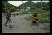 Two U.S. marines from ANGLICO seize a civilian during the U.S. invasion of Grenada. | Location: Grenada.