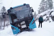 Der Busfahrer steht neben dem Bus, der sich au&szlig;erhalb der Stra&szlig;e in den Schnee geneigt hat. Er kam von der Stra&szlig;e ab, als er den Pflugmarkierungen folgte, die zu weit au&szlig;en im Graben angebracht waren. (National Geographic)