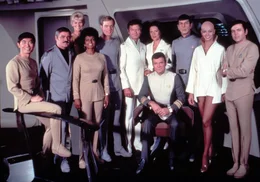 Die Besatzung der Enterprise von links: Lt. Commander Hikaru Sulu (George Takei), Lt. Commander Montgomery Scott (James Doohan), Janice Rand (Grace Lee Whitney), Lt. Commander Nyota Uhura (Nichelle Nichols), Commander Willard Decker (Stephen Collins), Dr. Leonard McCoy (DeForest Kelley), Dr. Chapel (Majel Barrett),  Admiral James T. Kirk (William Shatner), Commander Spock (Leonard Nimoy), Lieutenant Ilia (Persis Khambatta) und Lieutenant Pavel Chekov (Walter Koenig).