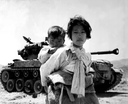 Mit ihrem Bruder auf dem R&uuml;cken stapft ein koreanisches M&auml;dchen m&uuml;de an einem M-26-Panzer vorbei in Haengju, Korea. 9. Juni 1951.