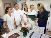 Sarah Marquardt (Alexa Maria Surholt, rechts) stellt im Schwesternzimmer ihr Konzept zur Effizenzsteigerung der Pfleger und Schwestern vor. Jede einzelne T&auml;tigkeit hat ab jetzt einen fest bemessenen Zeitrahmen. Das Pflegepersonal reagiert etwas befremdlich auf diese Neuerung. Doch als Sarah erkl&auml;rt, das Konzept sei mit Chefarzt Dr. Stein besprochen und von ihm abgesegnet, m&uuml;ssen sie sich damit anfreunden - von links: Schwester Arzu Ritter (Arzu Bazman); Pfleger Hans-Peter Brenner (Michael Trischan); Schwester Yvonne Habermann (Maren Gilzer); Oberschwester Ingrid Rischke (Jutta Kammann) und Sarah Marquardt (Alexa Maria Surholt).