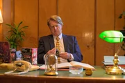 Ein Mann sitzt an einem Tisch und h&auml;lt ein Spielzeug