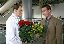 Dr. Peter Grainernapp (Heio von Stetten, re.) und sein Kollege Dr. Neumann (Anian Zollner) wollen beide einer verehrten Mitarbeiterin zum Geburtstag gratulieren.