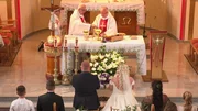 Photograph from the church. The priests are standing behind the altar, the bridal couple is in front of them. The wedding guests are kneeling on the church benches. Photograph from the church. The priests are standing behind the altar, the bridal couple is in front of them. The wedding guests are kneeling on the church benches.