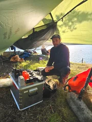Auch die Kamera-Technik muss vor Wind und Wetter gesch&uuml;tzt werden - Tonmann Chris bewacht seine Ausr&uuml;stung bei einem Stopp auf der Insel N&oslash;tter&oslash;y.