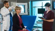 Dr. Theresa Koshka (Katharina Nesytowa, r.) vermutet hinter dem Haarausfall von Barbara Pohl (Silke Matthias, M.) eine medizinische Ursache. Sie zieht Dr. Matteo Moreau (Mike Adler, l.) zu Rate.