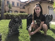 Keira stellt Grabsteine aus Plastik im Vorgarten auf.