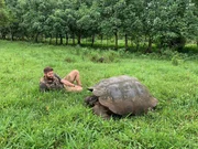 Forrest Galante In The Grass Next To A Galapagos Tortoise