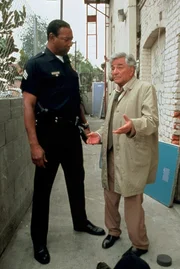 Ein in der Raveszene verhasster Klatschreporter hat angeblich Selbstmord begangen. Lt. Columbo (Peter Falk, re.) spricht mit dem Polizisten (Justin Carrey), der zuerst am Tatort eingetroffen ist.