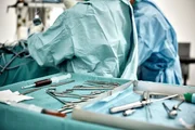 Close-up of surgical equipment in tray on table against surgeons at operating room