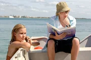 Lewis (Angus McLaren, li.) studiert ein Buch mit mystischen Seewesen, w&auml;hrend Emma (Claire Holt) als Meerjungfrau im Meer unterwegs ist.