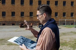 Dr. Stefan H&ouml;rdler mit Foto erkl&auml;rend vor Zellenbau KZ Lichtenburg