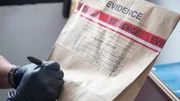 Forensic's hand in black glove writing on evidence bag and seal by red tape in crime scene investigation Forensic's hand in black glove writing on evidence bag and seal by red tape in crime scene investigation