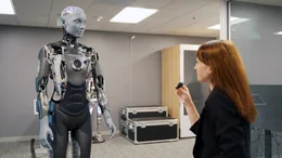 Ob virtuelle Assistenten - sogenannte Chatbots -, autonome Fahrzeuge, Smart Homes, Texte erstellt von ChatGPT, sekundenschnell in hunderte Sprachen &uuml;bersetzt, oder t&auml;uschend echte Medieninhalte bekannt als "Deepfakes". K&uuml;nstliche Intelligenz hat in unserem Alltag Einzug gehalten. Dennoch ist keine andere Technologie der Digitalisierung mehr umstrittener als sie. Wer sind die Gewinner und wer die Verlierer der Entwicklung, und wo liegen die Gefahren, wenn KI ohne unser Wissen, ohne unsere Zustimmung zum Einsatz kommt? Im Bild: Korrespondentin Vanessa B&ouml;ttcher lernt im Silicon Valley einen der fortschrittlichsten Roboter der Welt kennen. Ameca ist ein humanoider Roboter der mittels k&uuml;nstlicher Intelligenz im wahrsten Sinne des Wortes zum Leben erweckt wurde.