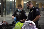 CBP-Beamter Axson schneidet ein Paket auf, das im Gep&auml;ck eines Passagiers gefunden wurde, w&auml;hrend CBP-Aufsichtsbeamter Beran in Atlanta, Ga. zusieht (National Geographic for Disney).